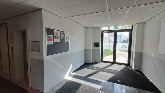 a corridor with a glass door and a checkered floor in a building