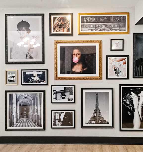 A wall of framed pictures with a black door on the left at Chateau on Wells, Chicago, Illinois