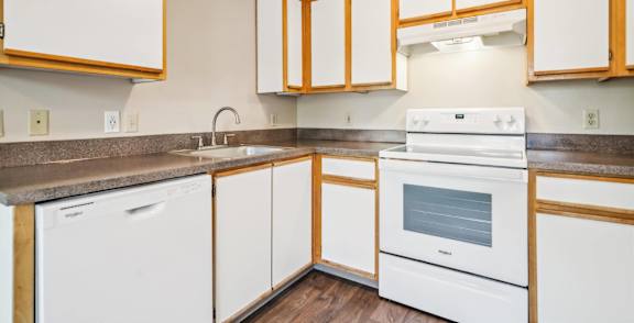 A kitchen with white appliances and wooden cabinets.
