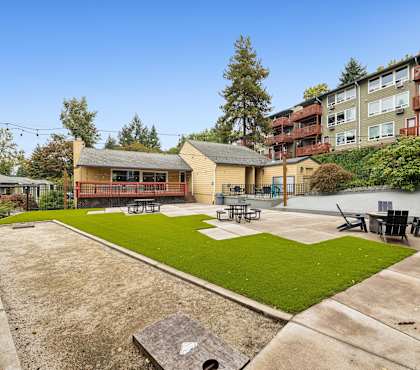 A sunny day at a park with a playground and apartment buildings in the background.