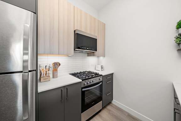 A modern kitchen with a stainless steel refrigerator and a black microwave above the stove.