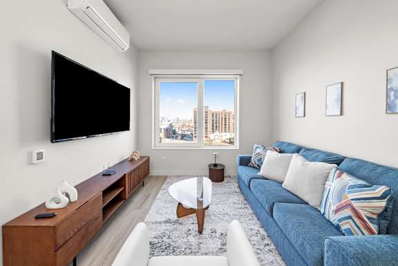 A living room with a blue couch and a flat screen TV mounted on the wall.