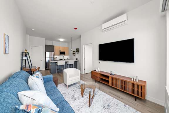 A living room with a blue couch and a television on the wall.