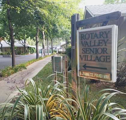 a sign for rotary valley senior village on the side of a sidewalk