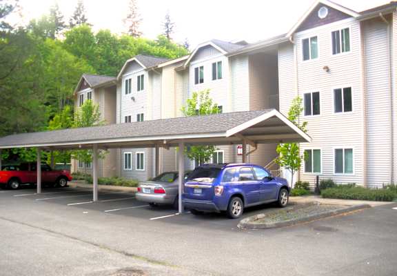 A blue car is parked in a parking lot in front of a building.