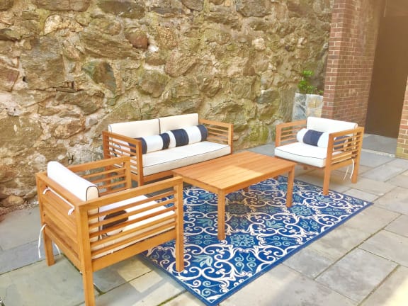 a wooden patio set with two chairs and a coffee table on a blue and white rug