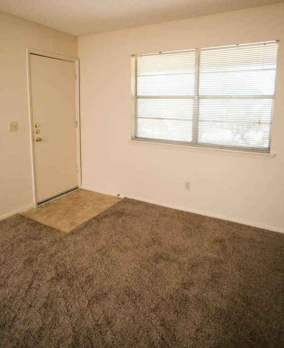 an empty living room with a ceiling fan and a window