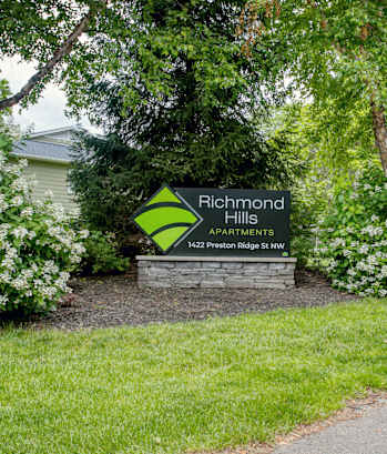 A sign for Richmond Hill Apartments sits in front of a green lawn.
