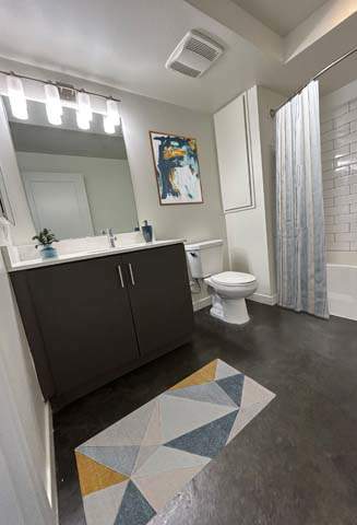 A bathroom with a toilet, sink, and a painting on the wall.