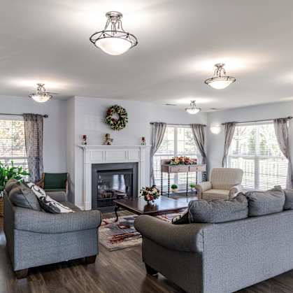 A living room with a grey couch, a green chair, and a fireplace.