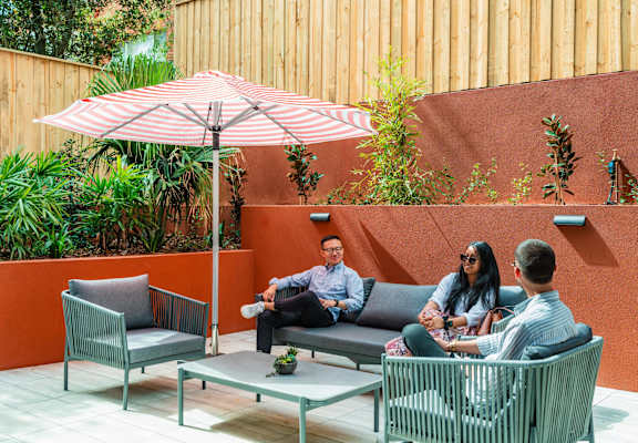 a group of people sitting on couches under an umbrella