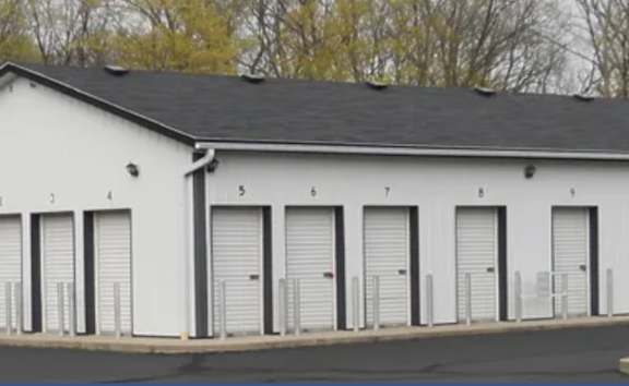 Three white storage buildings with roll-up doors.