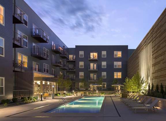 A modern apartment complex with a pool in the foreground.