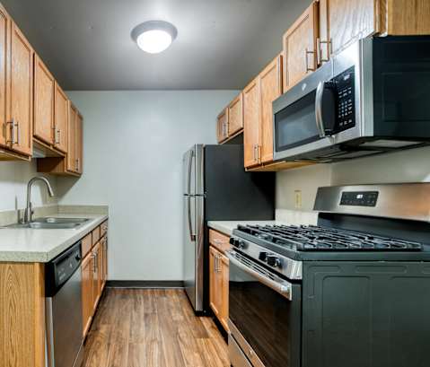 A kitchen with a black fridge and a black microwave.