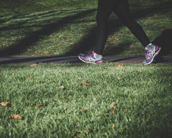 Jogger running on trail with grass