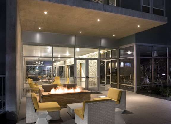 A modern patio with a fire pit and seating area.