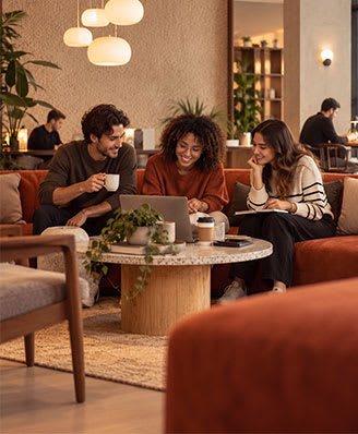Three people are sitting around a table in a cozy indoor setting.