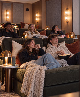 A group of people are sitting on a couch in a room with wall sconces.
