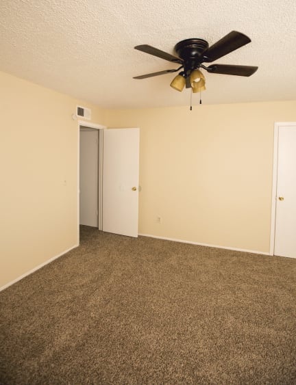 an empty living room with a ceiling fan and a door to a closet