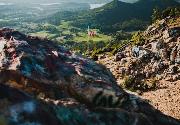 a flag on the top of a mountain overlooking a valley