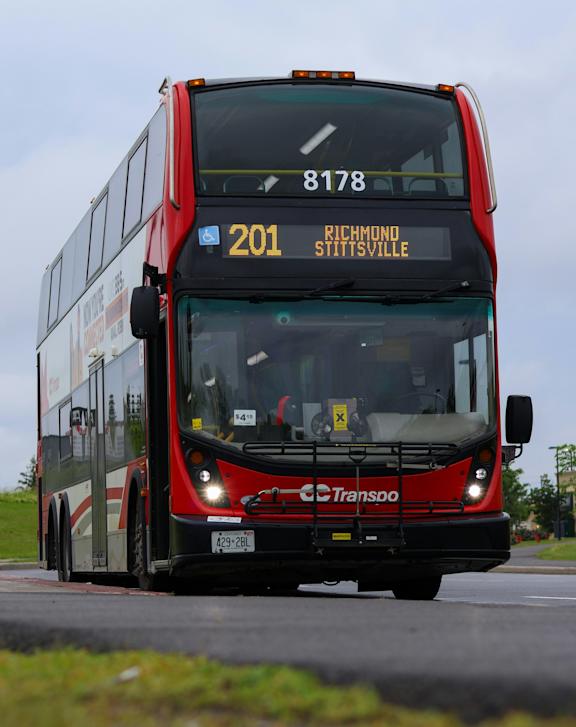 A red train with the logo "CC Transpo" on the front is at a station.