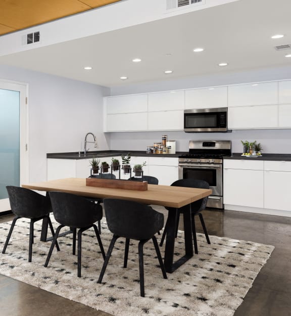 a kitchen with white cabinets and a table with black chairs