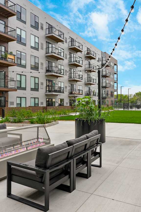 A modern outdoor seating area with benches and tables in front of apartment buildings.