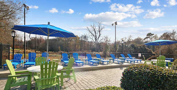 A sunny day at the park with blue umbrellas and green chairs.