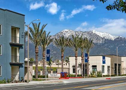 a city street with buildings and palm trees and mountains in the backgroundat Westbury Apartments, Rancho Cucamonga, California