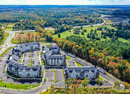 An aerial view of a large building surrounded by a parking lot and trees.