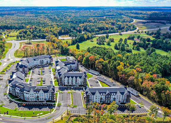 An aerial view of a large building surrounded by a parking lot and trees.