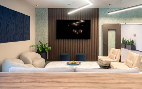 A modern living room with a large couch and a flat screen TV mounted on the wall.