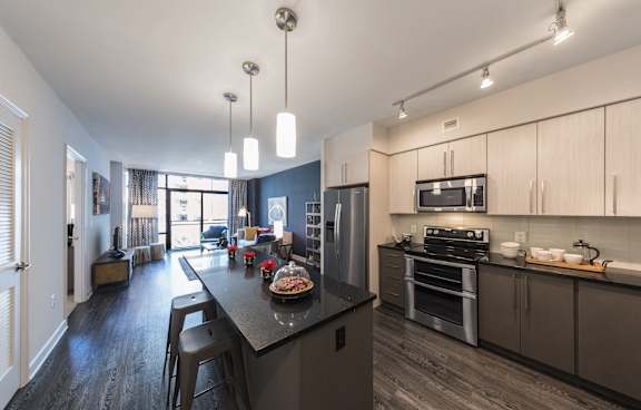 A modern kitchen with a black countertop and stainless steel appliances.