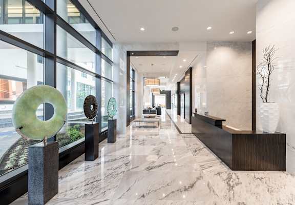 A long hallway with a marble floor and a large sculpture on the left.
