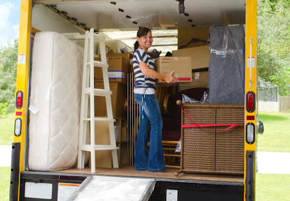 a woman loading a box into the back of a moving truck