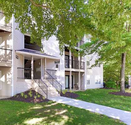 A white apartment building with a tree in front.