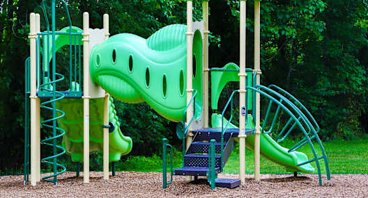 a playground with a large green dinosaur
