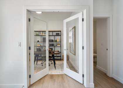 A white doorway opens to a room with a desk and chairs.