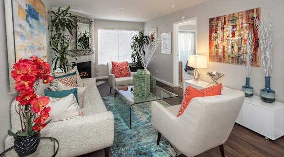A living room with a sofa, a chair, a table, and a painting on the wall.