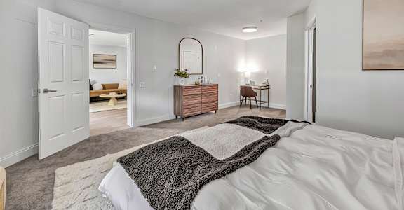 A bedroom with a large bed and a mirror on the wall.