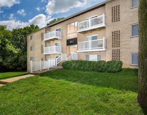Apartment building with balconies and a green lawn in front.