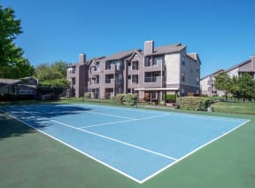 a tennis court with an apartment building in the background