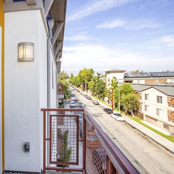 a balcony with a view of the street and a door to a apartment building