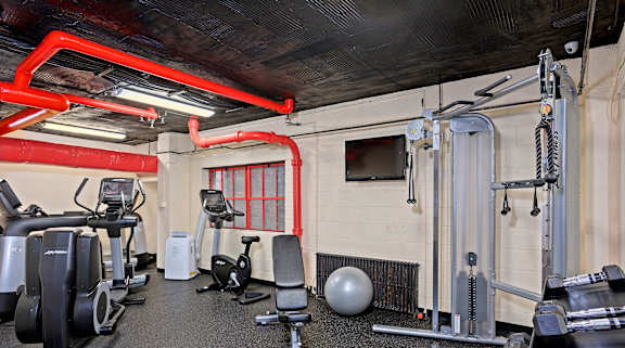 A gym with a variety of equipment including weights and cardio machines.