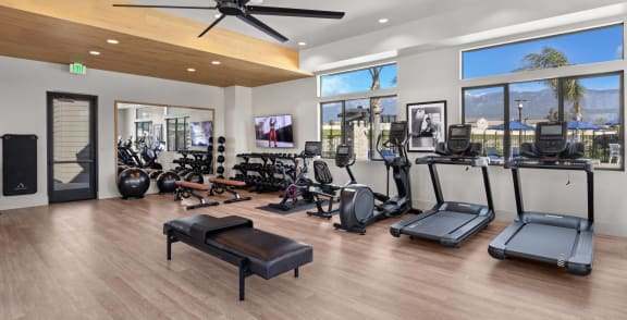 a gym with cardio machines and other exercise equipment in a building with large windows  at Westbury Apartments, Rancho Cucamonga, 91739
