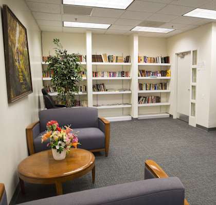 a waiting room in a library with chairs and a table with flowers