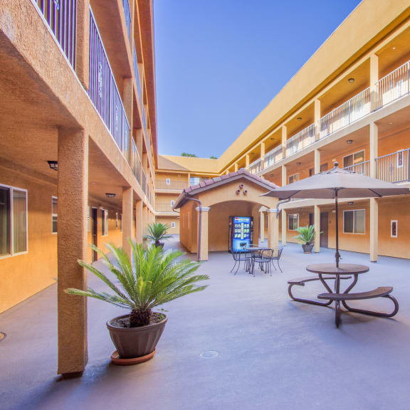 a courtyard with a table and umbrella in front of a building at Dronfield Astoria Apartments, Sylmar, California, 91342