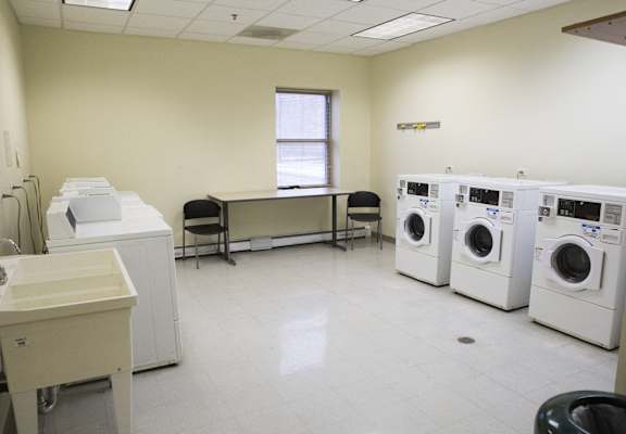 a washer and dryer room with a row of washing machines and a table