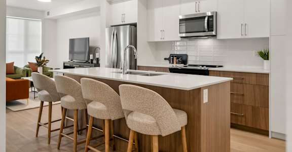 A modern kitchen with a bar area and white countertops.
