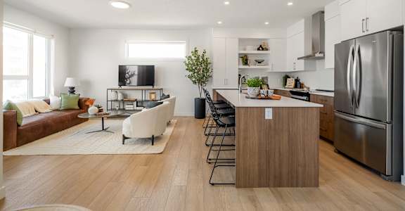 A modern kitchen with a refrigerator, stove, and island with a countertop and chairs.